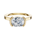 An 18K yellow gold half bezel East/West cathedral flat 2.0mm engagement ring is shown with a cushion-cut diamond in a modern minimalist setting, displayed on a plain white background.