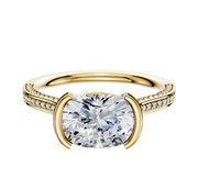 An 18K yellow gold engagement ring featuring a flat band with three rows of pave-set diamonds and a bezel half-bezel east/west cathedral setting.