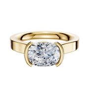 An 18K yellow gold half bezel East/West cathedral flat 3.0mm engagement ring features a modern, minimal design with a wide band and a cushion-cut diamond secured in a contemporary setting.