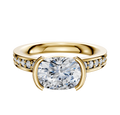 The 14K Yellow Gold Bezel Half Bezel East/West Classic Flat 1-Row-Pave 2.5mm Engagement Ring features a large oval diamond centerpiece and smaller pave diamonds along the band, shown against a white background.