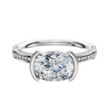 An 18K two-tone engagement ring featuring a classic flat band with three rows of pavé diamonds and a distinctive east/west-set center stone in a half bezel setting.