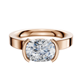 The 18K Rose Gold Bezel Half Bezel East/West Classic Flat 3.0mm Engagement Ring showcases a large cushion-cut diamond in a modern bezel setting, elegantly displayed against a plain white background.