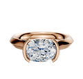 The 18K Rose Gold Bezel Half Bezel East/West Cathedral Knife Edge 3.0mm Engagement Ring features a cushion-cut diamond, secured in its unique east-west setting, and is displayed on a plain white background.