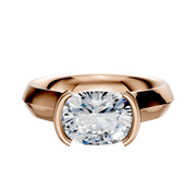 An 18K rose gold engagement ring with a wide knife edge band, featuring a 4.0mm cushion-cut clear gemstone in a modern, half bezel east/west cathedral setting.