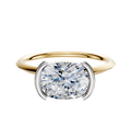 A 14K two-tone bezel half-bezel east/west classic knife edge 1.5mm engagement ring featuring a prominent round diamond in a modern setting.