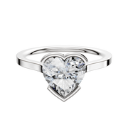 An 18K white gold bezel half bezel east/west cathedral flat 1.5mm engagement ring is showcased, featuring a large heart-shaped clear diamond set at the center against a plain white background.