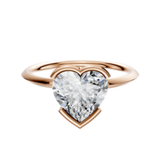 A 14K rose gold bezel half bezel east/west classic knife edge 1.5mm engagement ring with a large heart-shaped diamond solitaire, showcased on a plain white background.