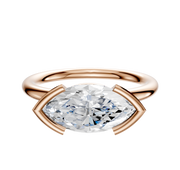 A 14K rose gold Bezel Half Bezel East/West Classic Dome 2.0mm engagement ring is shown, featuring a marquise-cut diamond set horizontally, displayed against a white background.