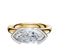 A 14K two-tone Bezel Half Bezel East/West Classic Dome 3.0mm engagement ring, featuring a marquise-cut diamond in a distinctive four-prong setting, is displayed against a plain white background.