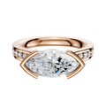 An 18K rose gold engagement ring featuring an east/west bezel-set center, a cathedral flat band, and a single row of pave diamonds along its 2.5mm width.