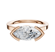 An 18K rose gold engagement ring featuring a half-bezel, east/west cathedral flat 2.0mm band, showcasing a marquise-cut diamond set horizontally in a modern minimalist style.