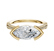 An 18K yellow gold engagement ring features an east/west cathedral setting with a central stone and 3-row pave diamonds along the flat band, shown on a plain white background.