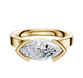 An 18K Yellow Gold Bezel Half Bezel East/West Classic Flat 3.0mm Engagement Ring is showcased on a plain white background, featuring a striking marquise-cut diamond secured in an elegant setting.