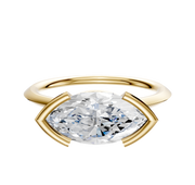 A 14K yellow gold engagement ring with a 1.5mm knife edge band and an east/west marquise-cut diamond in a half bezel cathedral setting, displayed on a plain white background.