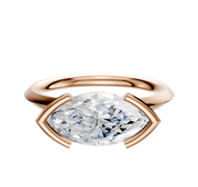An 18K rose gold East/West classic knife edge 2.0mm engagement ring with a half bezel setting is displayed against a plain white background.