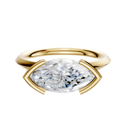 The 14K Yellow Gold Bezel Half Bezel East/West Classic Knife Edge 2.0mm Engagement Ring features a horizontally set gemstone in a sleek gold setting, shown against a plain white background.