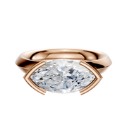 The 18K Rose Gold Bezel Half Bezel East/West Classic Knife Edge 3.0mm Engagement Ring showcases a large marquise-cut white diamond set horizontally in a modern, minimalist bezel against a white background.
