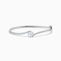 The Star Lab Grown Diamond Connect Bangle in 18K White Gold features a central round lab-grown diamond and a band set with small diamonds, all in an elegantly curved design, displayed on a white background.