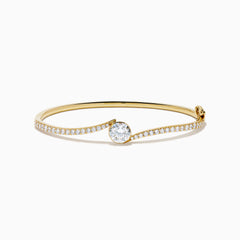 The Star Lab Grown Diamond Connect Bangle in 18K Yellow Gold features a central Star Lab Diamond with a row of smaller diamonds on an angled band, shown against a white background.