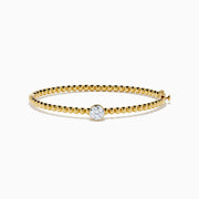 The Star Lab Grown Diamond Beaded Bangle in 18K Yellow Gold features a delicate gold band with beaded accents and a single round, clear lab-grown diamond at the center, shown against a plain white background.