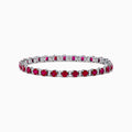 The Ruby Royale 18K White Gold Ruby and Diamond Tennis Bracelet showcases vibrant red rubies in individual prong settings, elegantly displayed against a plain white background.