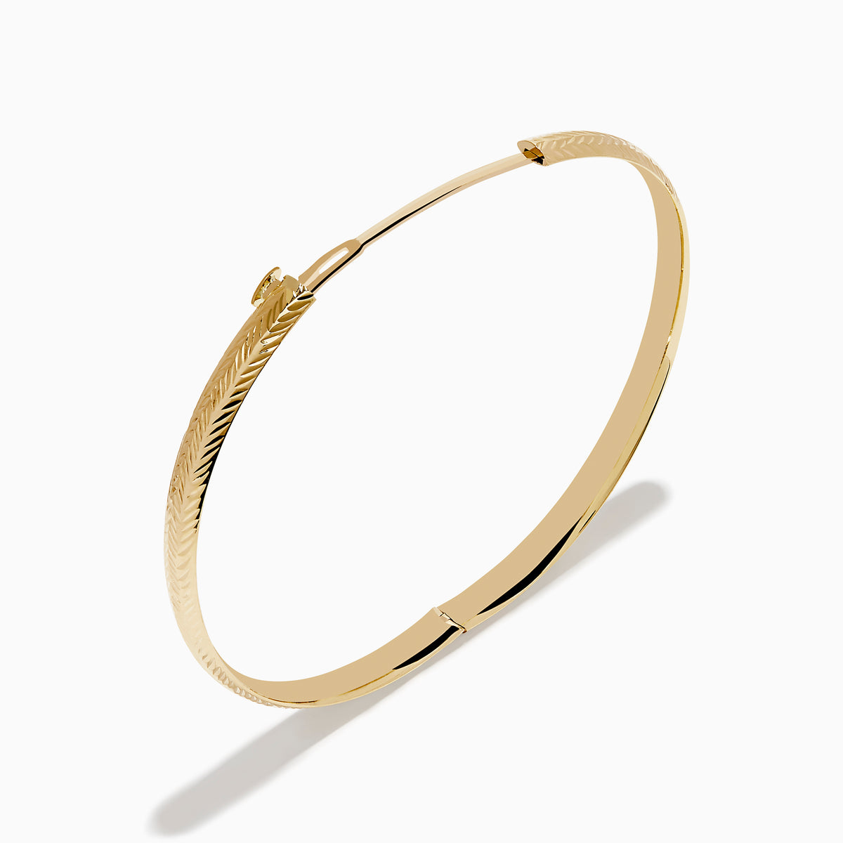 The 14K Yellow Gold Chevron Bangle features a subtle engraved pattern along its outer surface and is displayed on a white background.