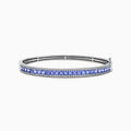 The Nahla Siri 14K White Gold Tanzanite and Diamond Bangle showcases a row of square-cut blue tanzanites between two rows of sparkling diamonds, elegantly displayed against a white backdrop.