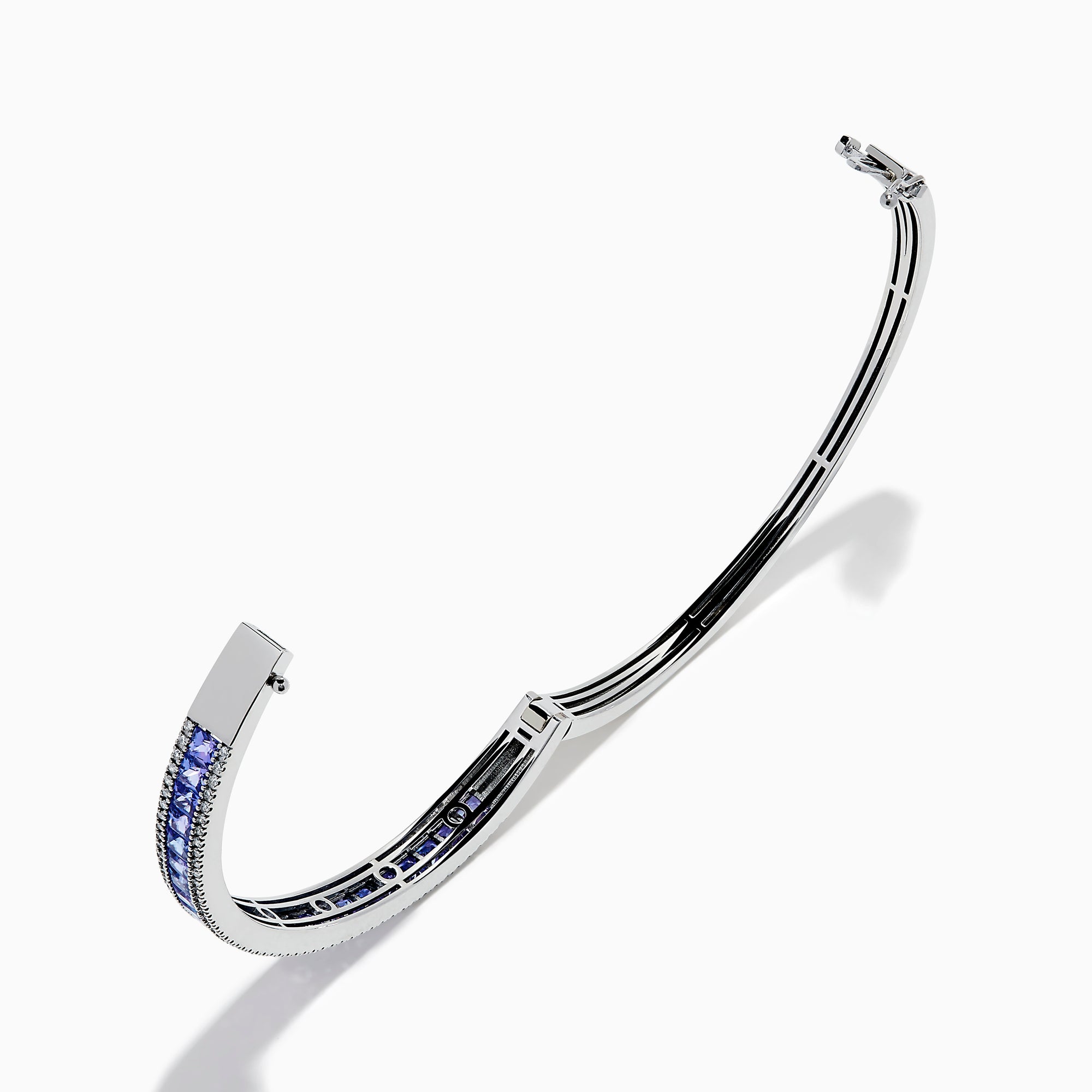 The Nahla Siri 14K White Gold Tanzanite and Diamond Bangle showcases a row of square-cut blue tanzanites between two rows of sparkling diamonds, elegantly displayed against a white backdrop.