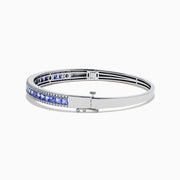The Nahla Siri 14K White Gold Tanzanite and Diamond Bangle showcases a row of square-cut blue tanzanites between two rows of sparkling diamonds, elegantly displayed against a white backdrop.