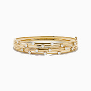 The D'oro 14K Yellow Gold Interwoven Crossover Bangle features multiple slim, interlaced bands adorned with evenly spaced round white gemstones, set in yellow gold for a radiant look.