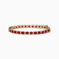 The Ruby Royale 14K Yellow Gold Ruby and Diamond Tennis Bracelet features a single row of round rubies and diamonds in prong settings, elegantly displayed against a white background.