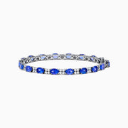 The 14K White Gold Tanzanite and Diamond Tennis Bracelet features alternating oval tanzanite gemstones and sparkling diamonds set against a plain white background.