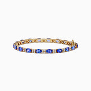 The 14K Yellow Gold Tanzanite and Diamond Tennis Bracelet showcases alternating round blue tanzanites and sparkling diamonds in a single row, secured with a reliable clasp.