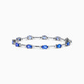 The 14K White Gold Tanzanite and Diamond Station Bracelet features vibrant oval-cut tanzanites and sparkling diamonds evenly spaced along the band, connected by delicate links for a timeless, elegant look.