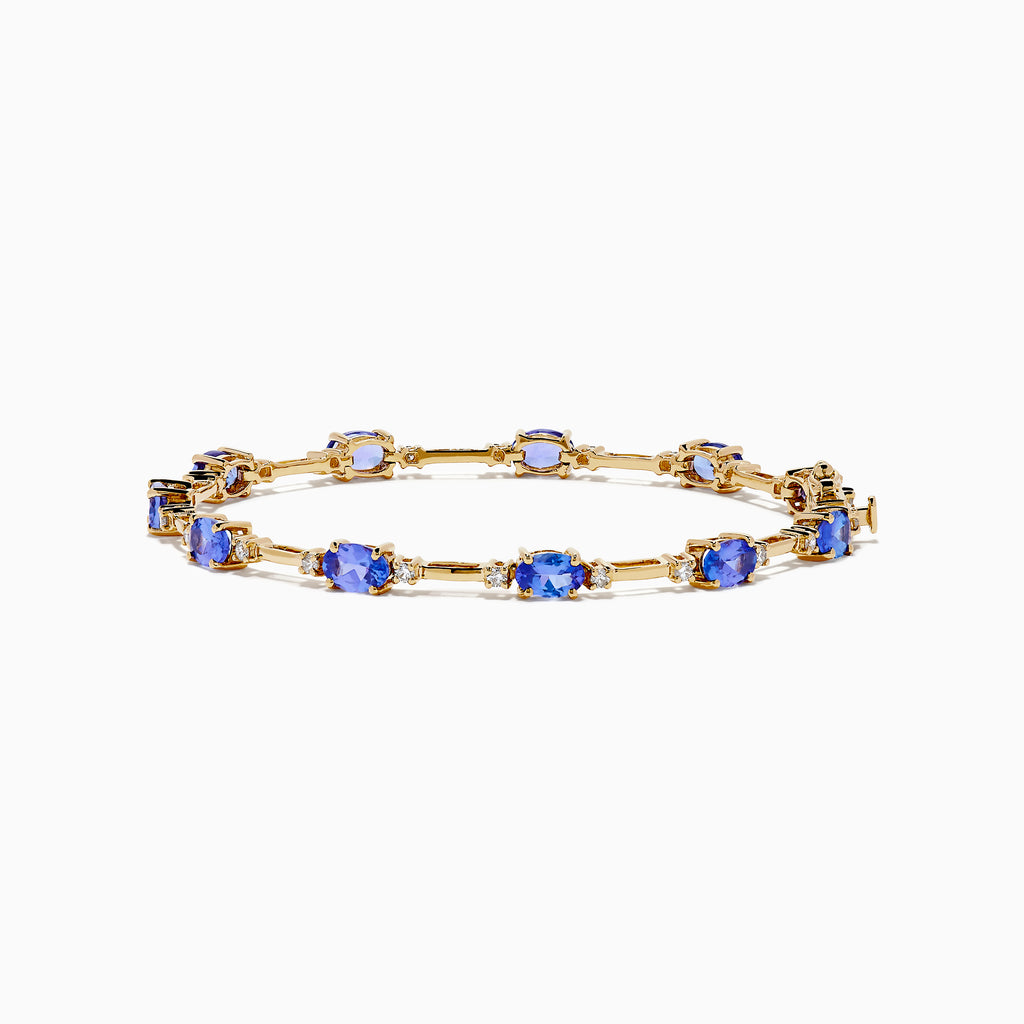The 14K Yellow Gold Tanzanite and Diamond Station Bracelet showcases evenly spaced oval tanzanites set in gold links, each accented by sparkling diamonds, creating an elegant look against a white background.