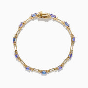 The 14K Yellow Gold Tanzanite and Diamond Station Bracelet showcases evenly spaced oval tanzanites set in gold links, each accented by sparkling diamonds, creating an elegant look against a white background.