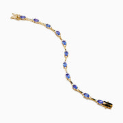 The 14K Yellow Gold Tanzanite and Diamond Station Bracelet showcases evenly spaced oval tanzanites set in gold links, each accented by sparkling diamonds, creating an elegant look against a white background.