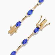 The 14K Yellow Gold Tanzanite and Diamond Station Bracelet showcases evenly spaced oval tanzanites set in gold links, each accented by sparkling diamonds, creating an elegant look against a white background.