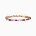 The 14K Yellow Gold Pink Sapphire and Diamond Tennis Bracelet features alternating oval pink sapphires and rectangular white diamonds set in an intricate yellow gold band.
