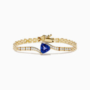 The 14K Yellow Gold Tanzanite and Diamond Chain Link Bracelet features a central triangular tanzanite gem, accented by rows of sparkling diamonds and a polished gold chain link band with a secure clasp.