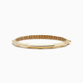 The 14K Yellow Gold Geometric Bamboo Bangle features an octagonal shape, a reflective surface, patterned textured sides in brown and gold hues, and slender raised edges inspired by geometric bamboo design.