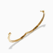 The 14K Yellow Gold Geometric Bamboo Bangle features an octagonal shape, a reflective surface, patterned textured sides in brown and gold hues, and slender raised edges inspired by geometric bamboo design.