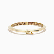 The 14K Yellow Gold Geometric Bamboo Bangle features an octagonal shape, a reflective surface, patterned textured sides in brown and gold hues, and slender raised edges inspired by geometric bamboo design.