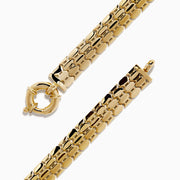 A thick, 14 karat yellow gold hollow snake skin bracelet with a round clasp, displayed in a circular shape on a white background.