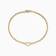 The 14K Yellow Gold Open Heart Rope Chain Bracelet 7.5 features a rope chain, an open heart centerpiece, and a secure lobster clasp, beautifully displayed on a plain white background.