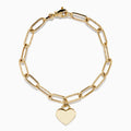 A 14K yellow gold paperclip chain bracelet featuring elongated textured links and a heart charm at the center, displayed on a white background.