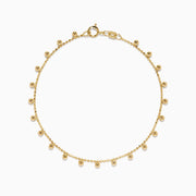The 14K Yellow Gold Tassel Bead Chain Bracelet features small, evenly spaced round charms on a delicate chain, finished with a secure lobster clasp closure.