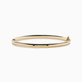 The 14K Yellow Gold Hollow Bangle features a smooth, round design with a small clasp, crafted in polished yellow gold and displayed on a white background.