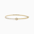 The D'Oro 14K Yellow Gold Pear Bezel Diamond Bangle showcases a row of small diamonds and a central pear bezel-set gem, all elegantly displayed against a plain white background.