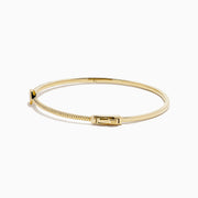 The D'Oro 14K Yellow Gold Pear Bezel Diamond Bangle showcases a row of small diamonds and a central pear bezel-set gem, all elegantly displayed against a plain white background.